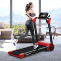 Woman using a red and black treadmill in a modern living room with large windows.