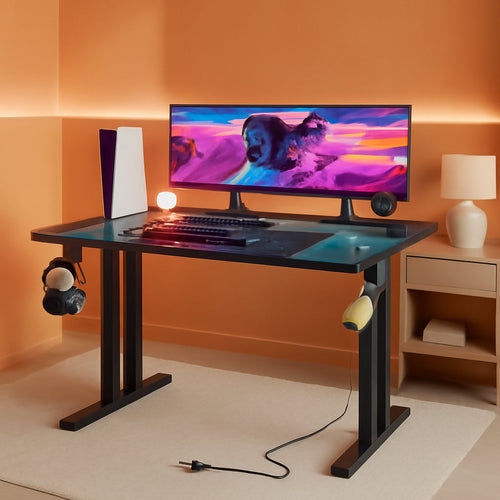 Modern home office setup with a desk, computer monitor, keyboard, and speakers against an orange wall.