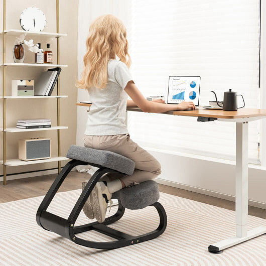 Person using an ergonomic kneeling chair at a desk in a home office setting
